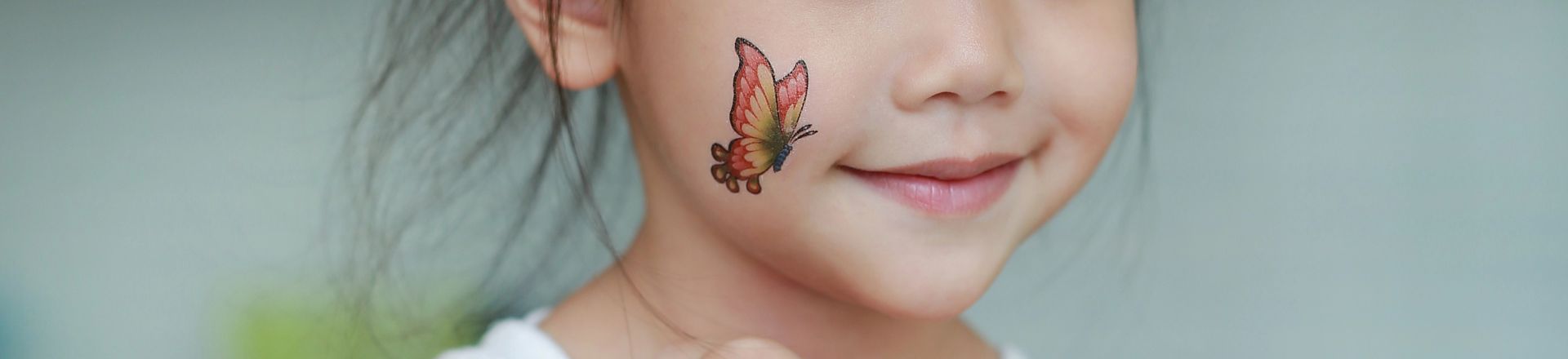 Close-up little child girl with butterfly tattoo sticker on body skin