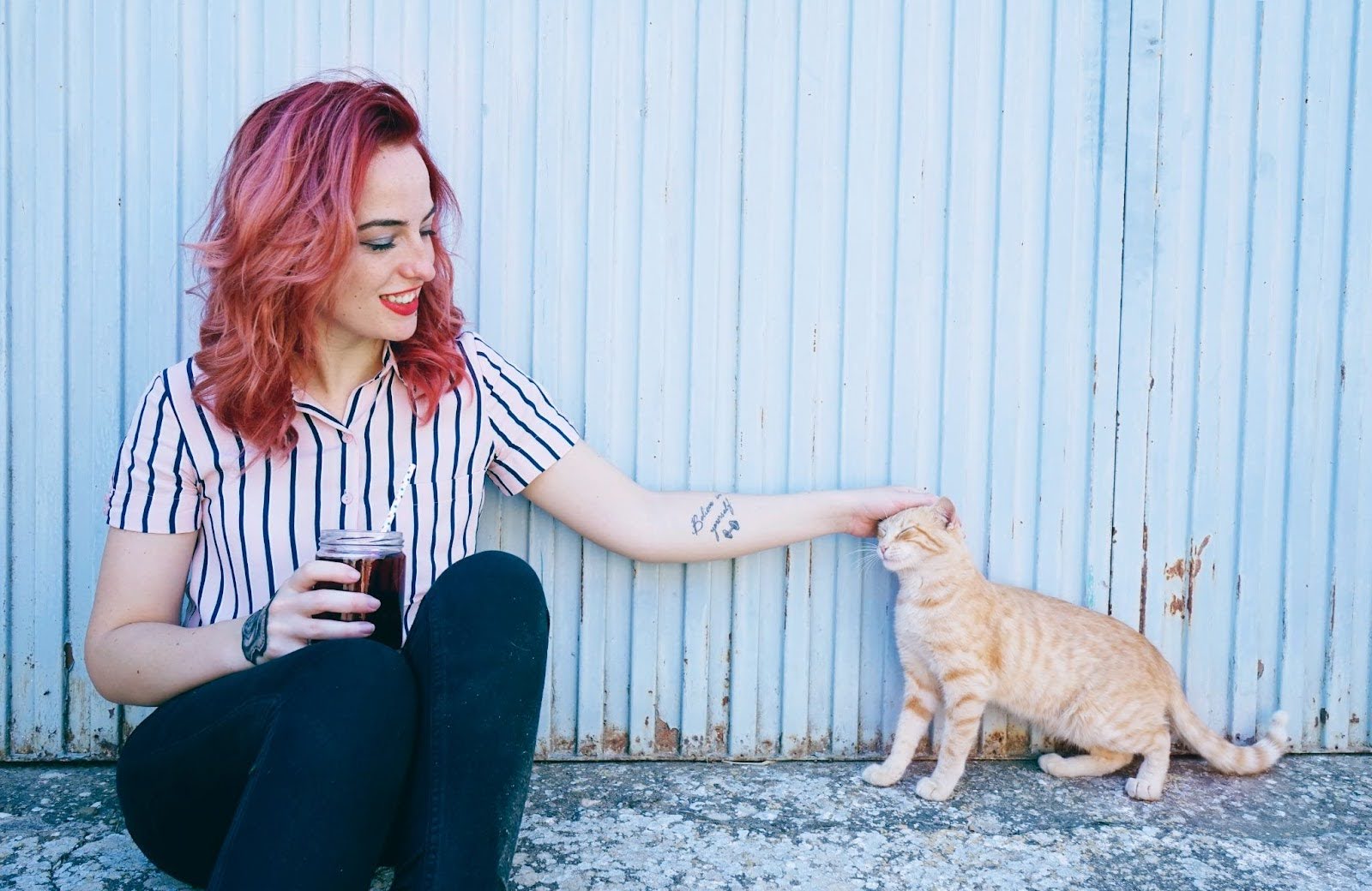 woman with pet tattoos petting orange cat